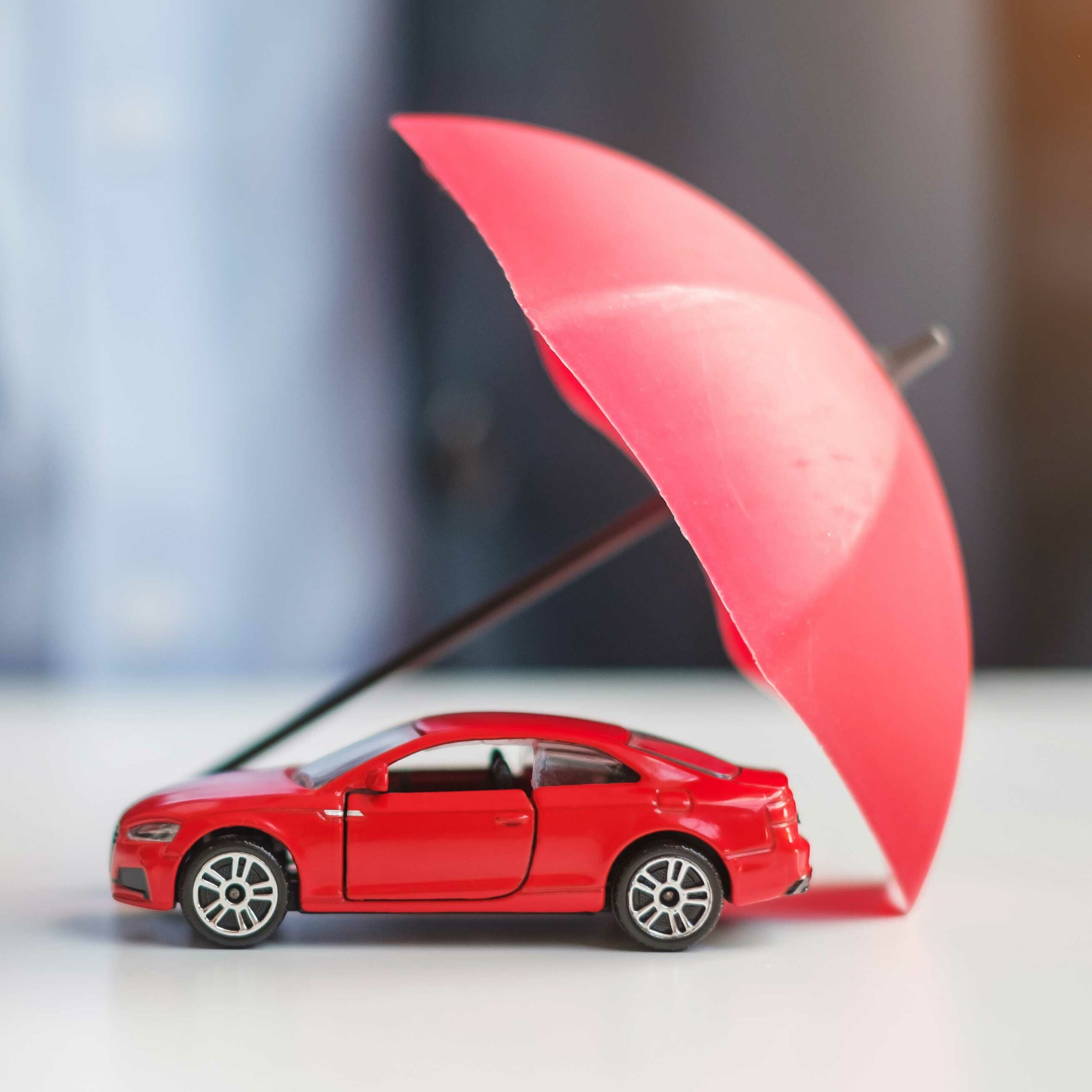 Voiture protégée par un parapluie représentant l'assurance pour son véhicule